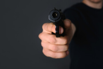 Man aiming gun on dark background, closeup
