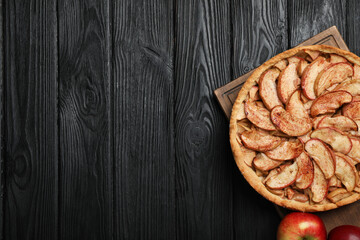 Delicious apple pie and fresh fruits on black wooden table, top view. Space for text