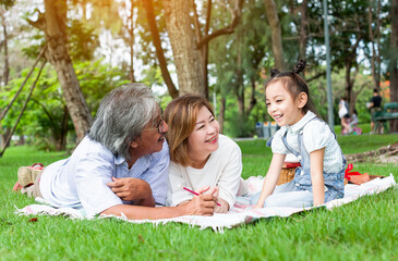 Fototapeta premium Grandfather and grandmother playing on the green grass with grandchildren in the park, Holiday with grandparents, Summer with grandparents, Concept family vacation lifestyle, Green nature background