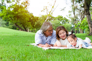 Fototapeta premium Grandfather and grandmother playing on the green grass with grandchildren in the park, Holiday with grandparents, Summer with grandparents, Concept family vacation lifestyle, Green nature background
