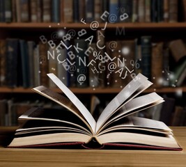 Old book with flying letters and magic light in library. Knowledge, history, memory and information.