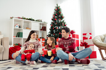 Photo of shiny sweet big family wear christmas sweaters sitting under tree drinking hot tea smiling indoors room home house