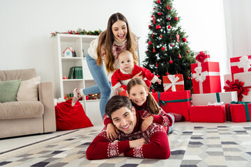Obraz na płótnie Canvas Photo of cute funny couple two children dressed new year pullovers smiling having fun together indoors house home room