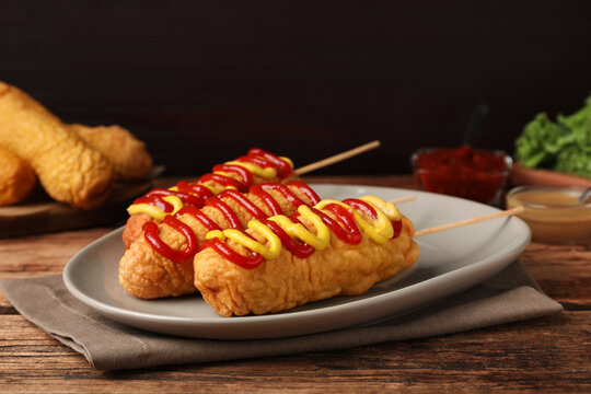 Delicious corn dogs with mustard and ketchup on wooden table - Powered by Adobe