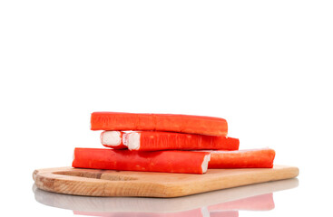 Several frozen crab sticks on a wooden cutting board, close-up, isolated on white.