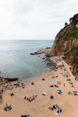 GIRONA, SPAIN - April 4, 2021: View of a beach full of people enjoying spring time in Tossa de Mar