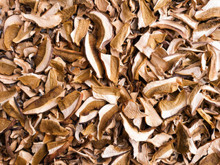 Dried slimes of fragrant Boletus mushrooms are scattered in a thin layer. Background for advertising a product of dried mushrooms.