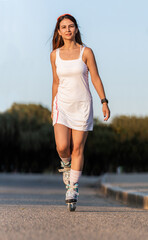 Young woman wearing dress skating with inline skate in a street