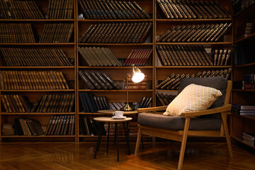 Cozy home library interior with comfortable armchair and collection of vintage books on shelves