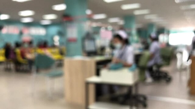 Blurred video of unidentified people and patients waiting to see the doctor at at reception desk with nurse in hospital in the scene. Waiting medicine concept. 4k video footage.