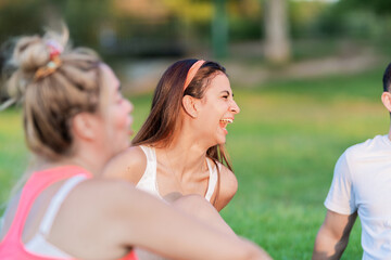 Fototapeta premium Selective focus on a woman laughing while sitting on a park with some friends