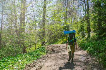 one man alone goes hiking with backpack in  forest