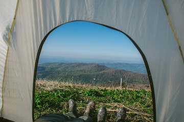 view from the tent, hiking in the mountains, two pairs of legs in hiking boots sticking out, rest