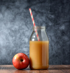 apple juice in the bottle with drinking straw - gray background - closeup