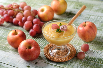 apple and grape mousse in glass cup with fruit around - closeup