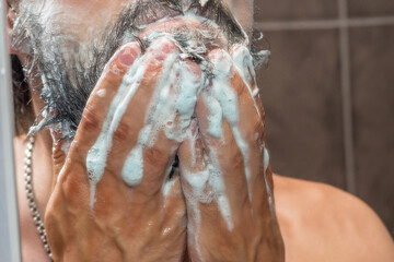 Beard care - a man washes his beard with soap foam - obrazy, fototapety, plakaty