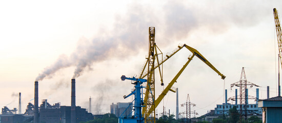 Port crane on the background of an industrial plant, air pollution
