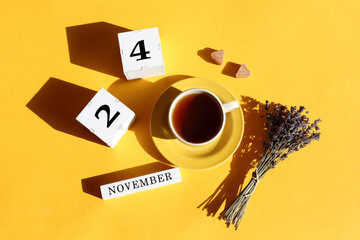 Calendar for November 24: cubes with the number 24, the name of the month in English, a cup of tea, two pieces of sugar in the shape of a heart, a bouquet of lavender, shadows from objects