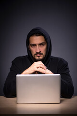 Young male hacker on grey background