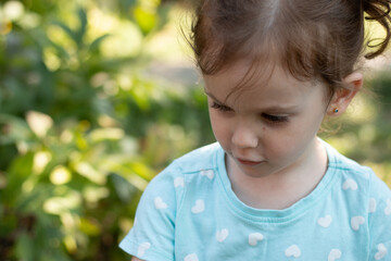Portrait of a beautiful young girl in a blue t-shirt on a blurred green natural background. Outdoor photo