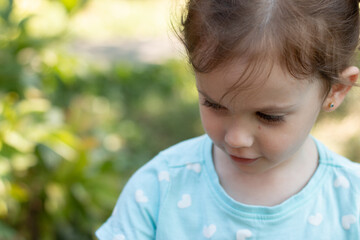 Portrait of a beautiful young girl in a blue t-shirt on a blurred green natural background. Outdoor photo