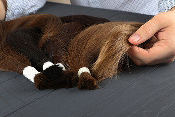 Man holding in hands different types of hair.Blond,red and brown-haired sections.Hair extensions concept. © Bidzilya