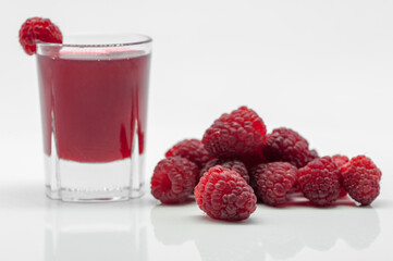 glass with raspberry alcoholic drink and raspberries on white background  