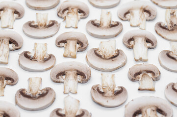 sliced champignons mushrooms on a white background arranged as a pattern