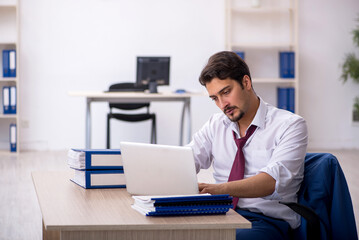 Young male employee unhappy with excessive work in the office