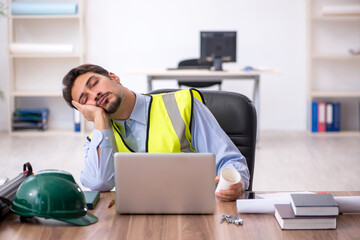 Tired young male architect drinking coffee during break