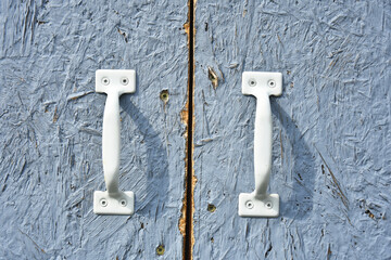 A close up image of old metal door handles on a garden shed. 