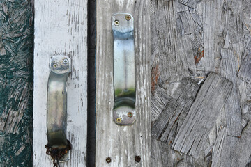 A close up image of old metal door handles on a garden shed. 