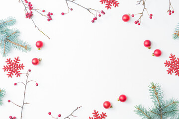 Flat lay christmas frame with red berries, fir branches, snowflakes and red balls on a white background. Merry christmas card and copy space for your text