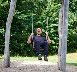 A young Hispanic man on a swing in a park