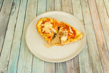 Top view image of Italian calzone with mozzarella cheese, tomato, cooked ham and mushrooms
