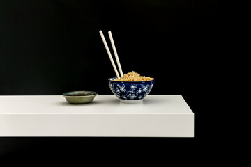 Freshly cooked rice in a blue porcelain bowl with drawn flower motifs and soy sauce on the side