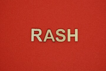 Fototapeta na wymiar text the word rash from gray wooden small letters on an red table