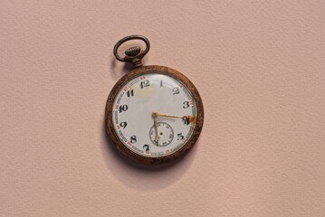 one white old pocket watch lies on a brown table