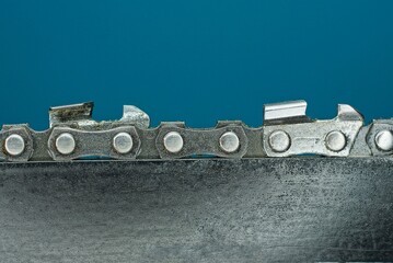 part of a black electric saw with gray sharp iron teeth on a blue background