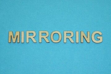 Fototapeta na wymiar gray word mirroring in small wooden letters on a blue background
