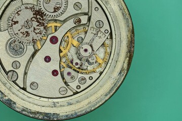 Fototapeta na wymiar metal mechanism of an old gray round clock lies on a green table