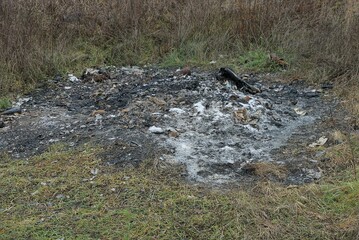 black gray ash from a large extinct fire on the ground and green grass in nature