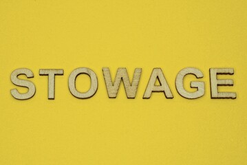 word stowage made from wooden letters lies on a yellow table
