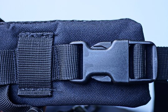 one closed black plastic latch on the harness of the backpack on a white background