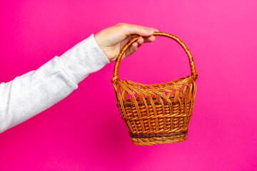 Wicker basket in hand. Handmade basket. Pink background