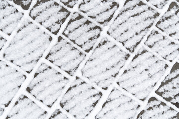 White snow lies on a cold surface. Abstract pattern. Textured cobblestone covering.