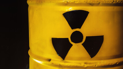 Yellow metal barrel with radioactive decay symbol. Container with nuclear trefoil warning sign....