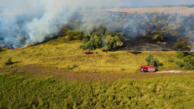 Top view of invincible forest conflagration and climbing smoke and fire fighting vehicle engine. Natural disaster on huge scale