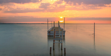 Ponton pour la pêche au bord d'un étang en Camargue dans le sud de la France au coucher du soleil.	