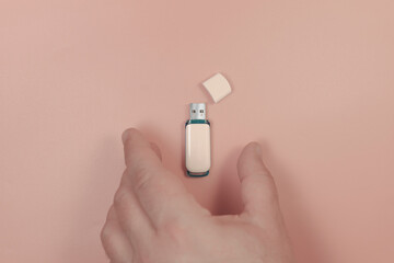 The hand takes a USB stick. On a pink background. Close-up